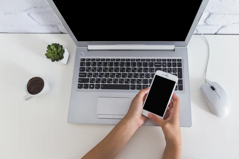 woman-using-cellphone-laptop-desk